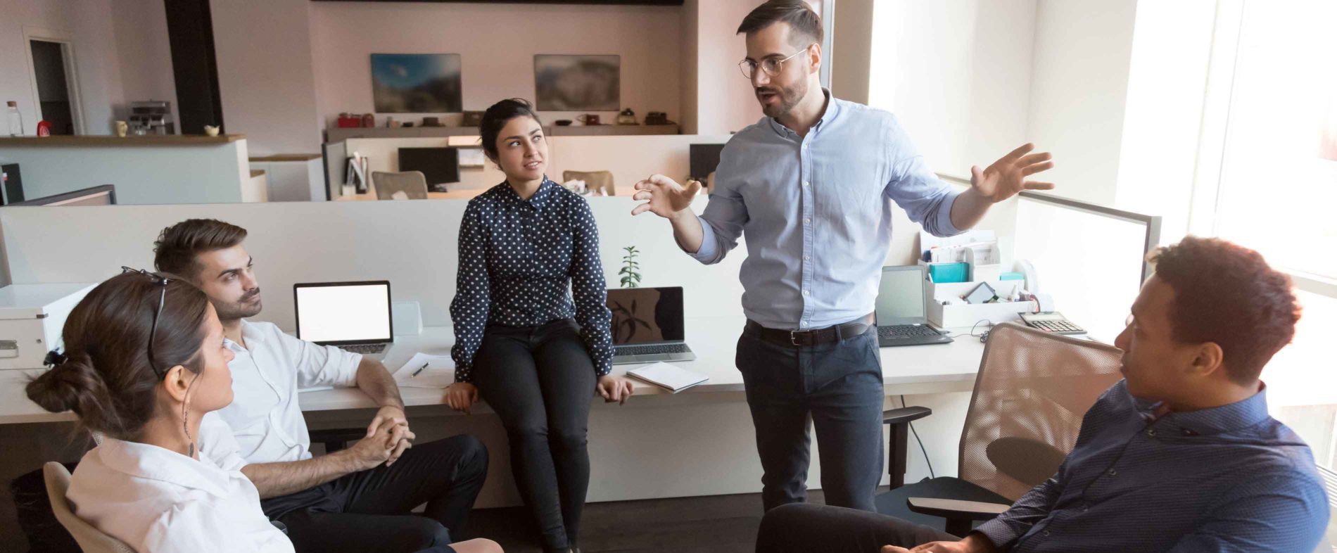 Five people in a circle having a discussion in an office setting