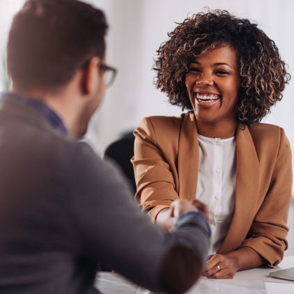 a Black woman shaking hands with a man in an office setting