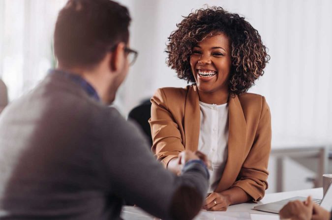 a Black woman shaking hands with a man in an office setting