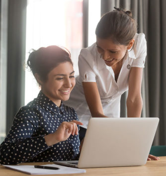 two women having a discussion over a laptop in the workplace